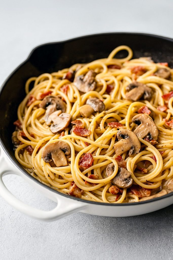 Creamy spaghetti with mushrooms and crispy bacon in a white sauce, served in a white bowl – perfect for Spaghetti And Mushroom Recipes, Entrees With Mushrooms, and cozy Easy Fall Pasta Recipes.