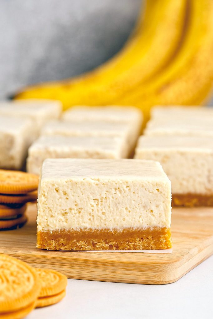 Close-up of three creamy cheesecake bars stacked on a white plate, revealing a golden crust and swirls of real banana filling—perfect for Banana Dessert Recipes, fans of Banana Cheesecake, or anyone craving a dreamy Banana Dessert.