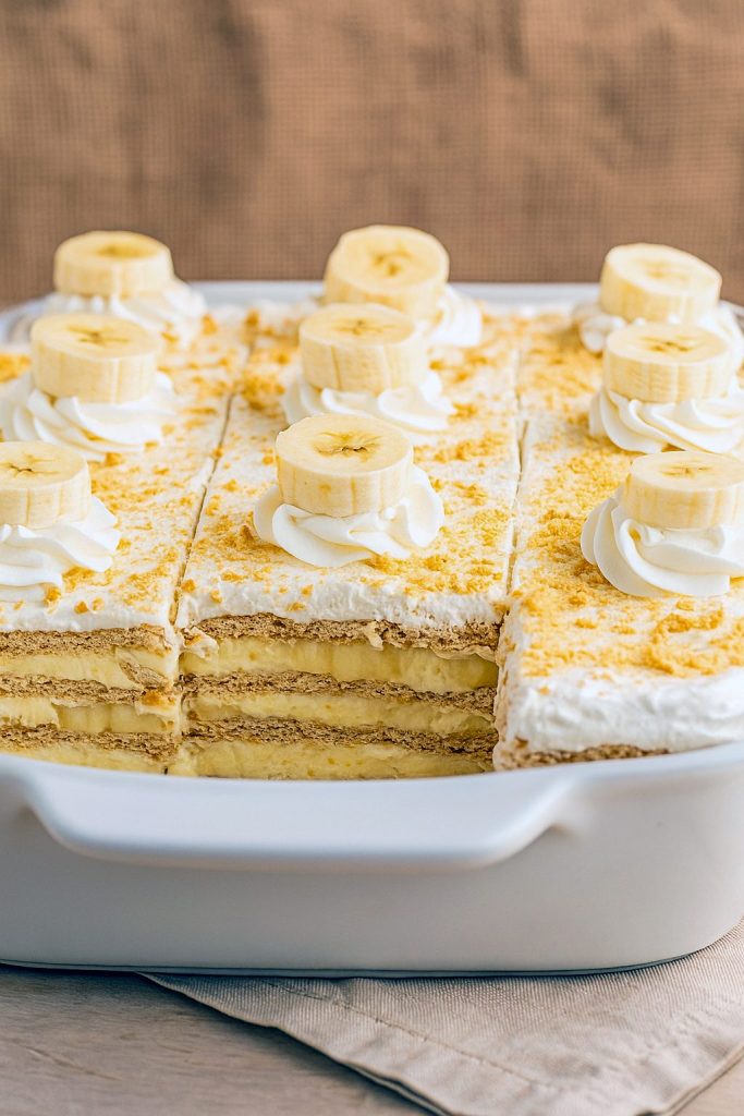 A layered Icebox Cake made with creamy banana pudding, whipped topping, sliced bananas, and Biscuits Graham, perfect for fans of Easy Chocolate Banana Icebox Cake, No Bake Banana Pudding, and retro-style Banana Dessert Recipes.