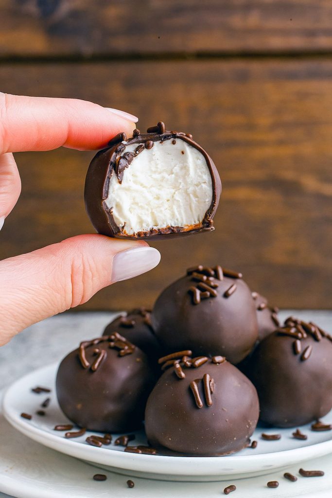 Close-up of round chocolate-coated truffles resting on parchment paper, each revealing a creamy buttercream center.