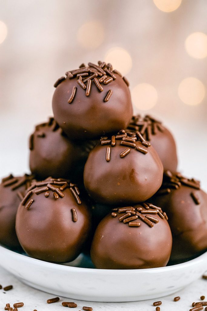 Close-up of round chocolate-coated truffles resting on parchment paper, each revealing a creamy buttercream center.