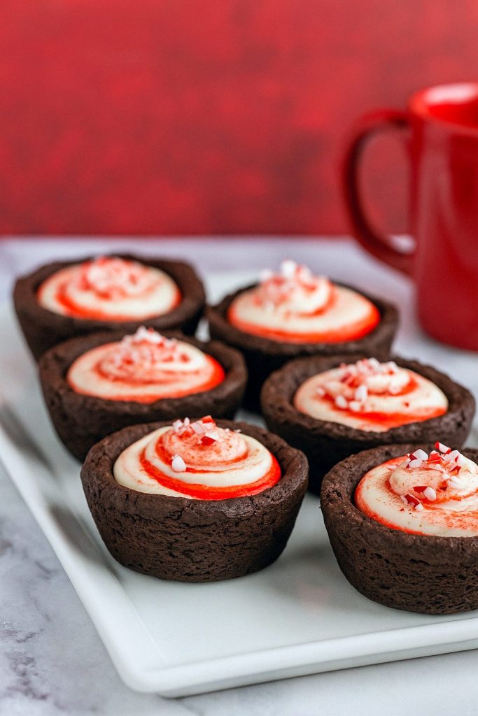 Dark chocolate cookie cups piped with minty cheesecake filling and sprinkled with crushed candy canes.