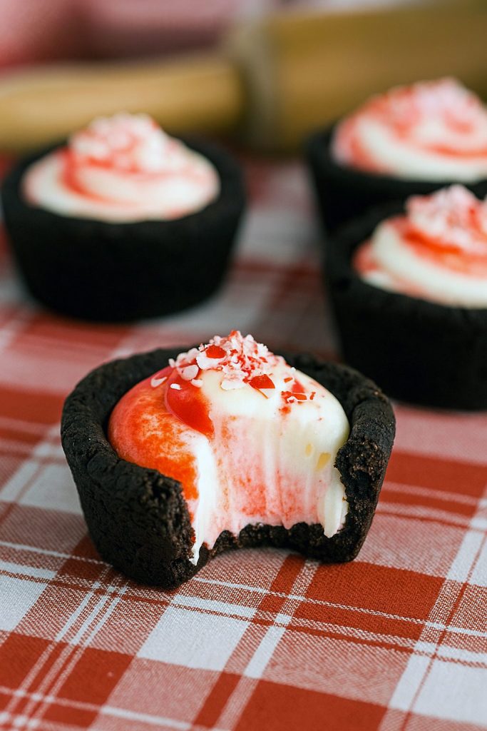 Dark chocolate cookie cups piped with minty cheesecake filling and sprinkled with crushed candy canes.