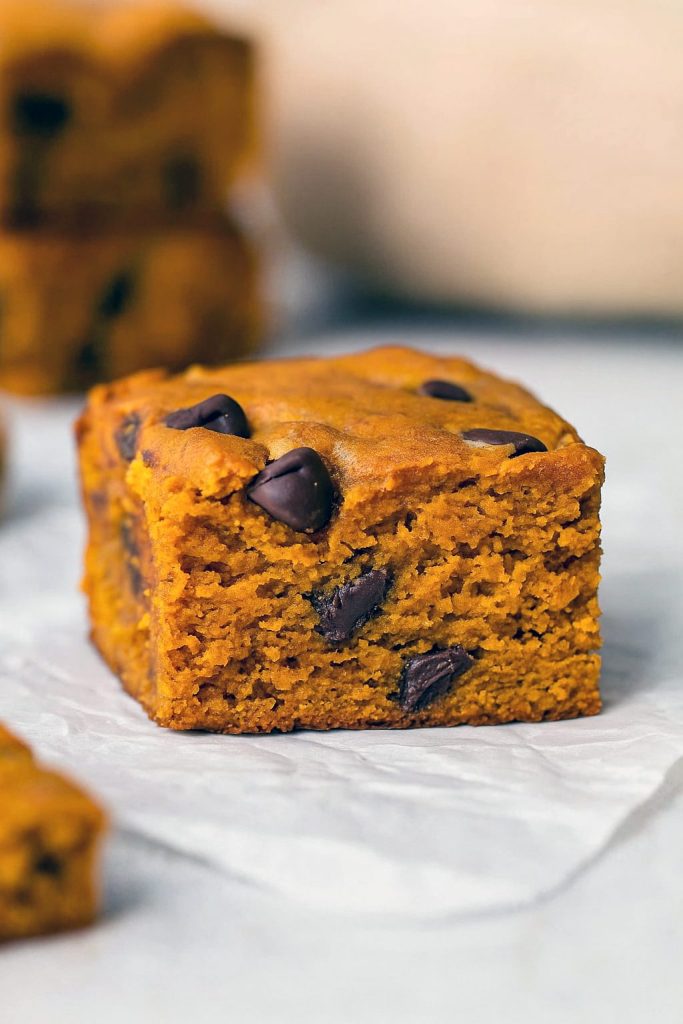 A tray of thick, chewy Pumpkin Spice Blondies studded with melty Chocolate Chip Bars, showcasing the gooey texture of a Pumpkin Blondies Recipe Easy and the cozy warmth of fall spices. Perfect for a Dessert Party, these squares echo both Chocolate Chip Blondies and a hearty Pumpkin Spice Blondie Recipe With Pumpkin Puree, with options for Vegan Pumpkin Blondies Recipe or Pumpkin Blondies Vegan versions, making this the ultimate Pumpkin Blondies Recipe.