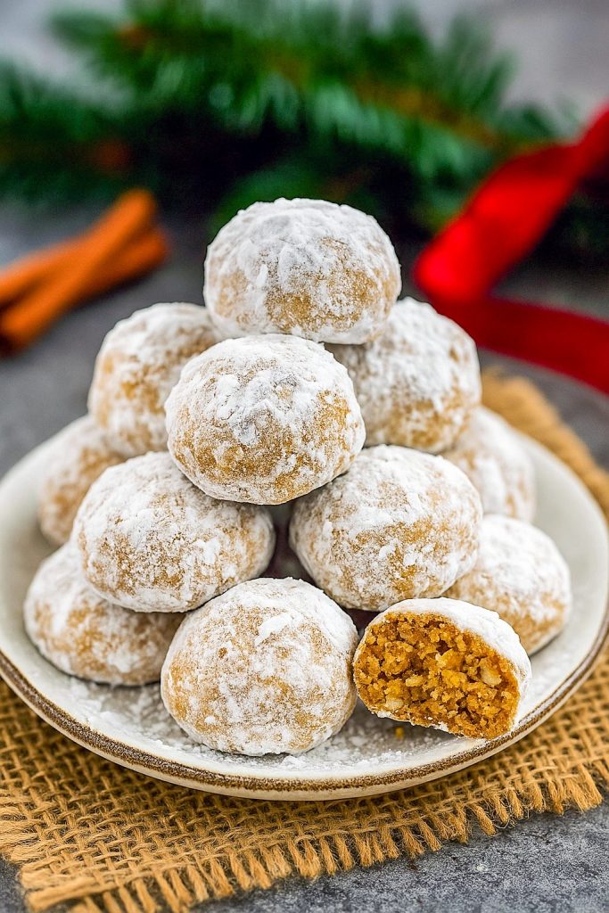 Close-up of powdered sugar-dusted gingerbread snowball cookie on a white plate, evoking festive Christmas Cookies Gingerbread, ready to complement Christmas Casserole Recipes and other Easy Xmas Desserts.