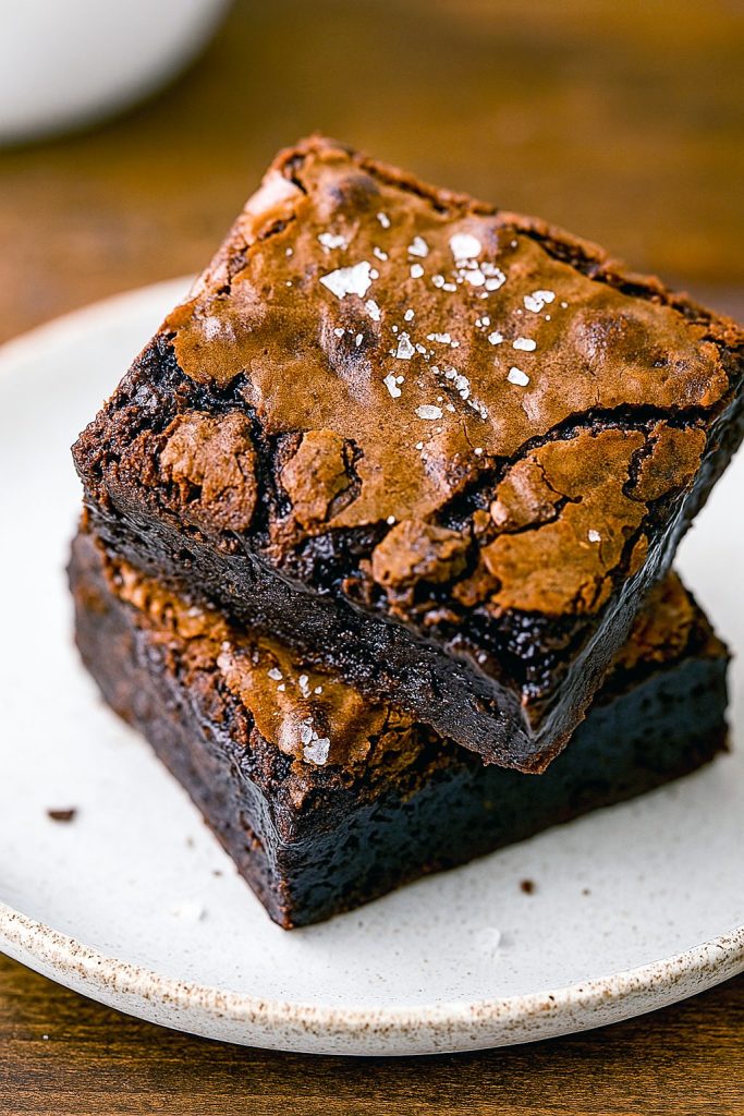 Close-up of shiny, crackly brownies stacked to highlight the fudgy center of Gooey Fudge Brownies, showcasing the deep color from the Best Brownie Recipe With Cocoa Powder.