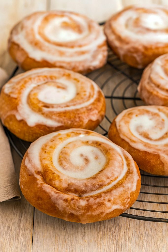 A stack of golden honey buns coated in a glossy glaze, cooling on a wire rack and ready to tempt any sweet tooth.