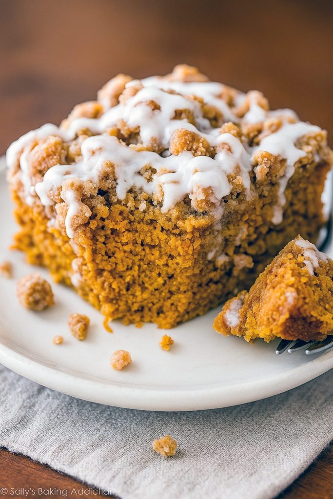 A slice of spiced pumpkin coffee cake with a golden streusel topping and vanilla glaze on a wooden board, illustrating a perfect fall treat. This photo showcases a Pumpkin Spice Coffee Cake Recipe, echoes a cozy Pumpkin Spice Latte Cake Recipe, and teaches How To Make Pumpkin Spice Latte Cake, while highlighting top Pumpkin Coffee Cake Recipes, an easy 3-ingredient Pumpkin Spice Cake, a festive Pumpkin Spice Coffee Cake Bundt, beloved Crumb Coffee Cakes, the ultimate Streusel Coffee Cake, and classic Pumpkin Coffee Cakes.