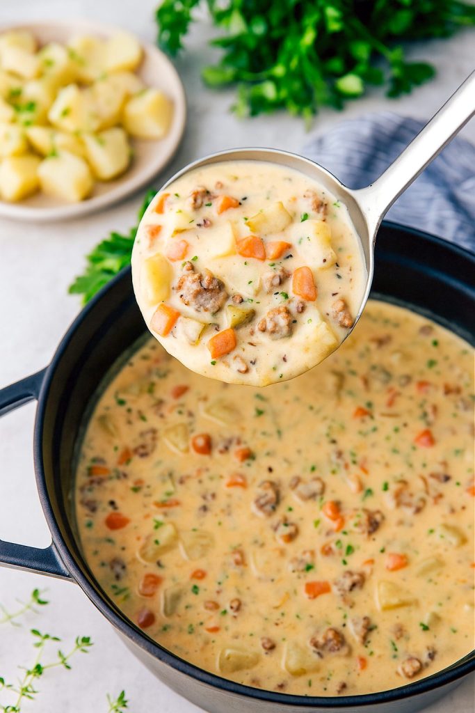 Hearty sausage and potato soup in a rustic bowl, garnished with parsley, showcasing tender potatoes and savory sausage in a creamy broth; the ultimate cozy winter meal.
