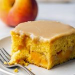 Slice of moist Peach Cake topped with rich brown sugar icing, loaded with Brown Sugar Peaches, and perfect for fans of Peach Cake Recipes and summery Peach Desserts. A must-try Peach Recipe and nostalgic USA Food favorite.