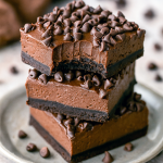 A square of rich, glossy no-bake chocolate cheesecake sitting on a dark plate, topped with mini chocolate chips—one of the easiest Chocolate Cheesecake Bars to make, showcasing a creamy Chocolate Cream Cheese filling in a chilled No Bake Bars treat from the world of Easy Chocolate Desserts and Cheesecake Bars, perfect for any Food Cakes collection.