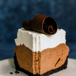 A deep‑dish pie with a dark Oreo crust, filled with smooth chocolate mousse, topped with pillowy whipped cream and chocolate shavings.