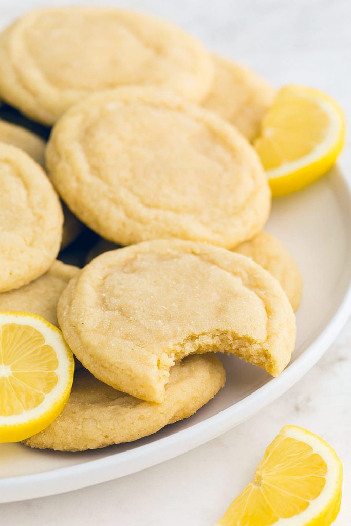 Stack of lemon cookies on a white plate with crinkled tops and golden edges, showing the texture of soft lemon sugar cookies and sparkle of lemon sugar, perfect for any cookie monster craving chewy lemon sugar cookies or quick lemon crinkle cookies from cake mix easy style treats.