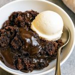 Close-up of a slice of gooey Hot Fudge Cake oozing sauce, garnished with toasted marshmallows and chocolate chunks for a cozy Smores Dessert twist, with a dollop of whipped cream and a hint of Coconut Dessert flair.