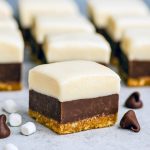 Square pieces of Smores Fudge stacked on a plate, showing chocolate, marshmallow, and graham cracker layers—an easy Layered Fudge from the best Fudge Dessert Recipes.