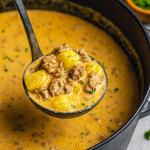 A steaming bowl of creamy potato soup topped with shredded cheddar and parsley, showcasing a rich base of ground beef and diced potatoes.