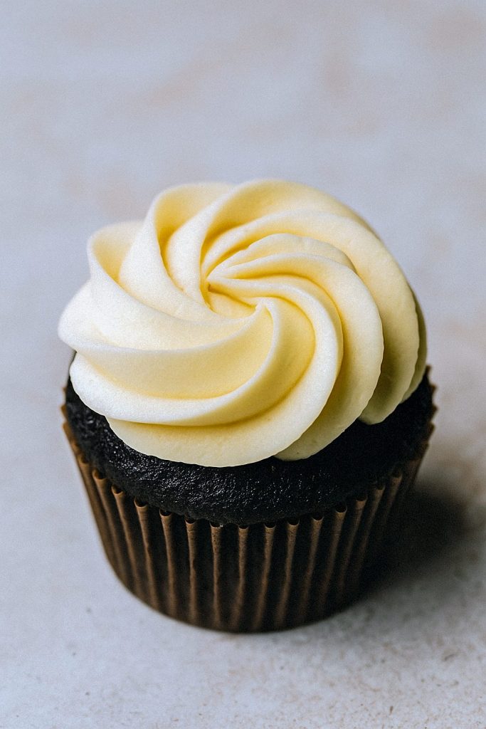 A bowl of fluffy Banana Buttercream Frosting with a spatula, ready to spread on a layer cake.