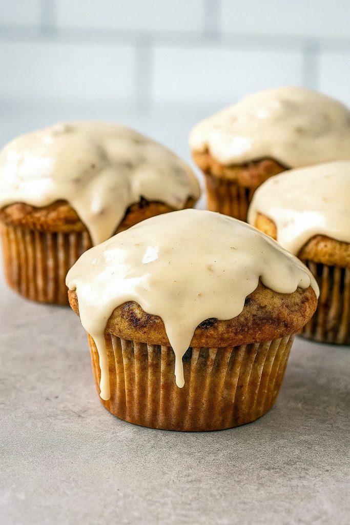 Close-up of soft and fluffy Muffins With Icing, swirled with cinnamon sugar and topped with Muffins With Cream Cheese Frosting, perfect for brunch, dessert, or Baking Homemade treats like Cinnamon Bun Muffins and Muffin Cinnamon Rolls from the best Cinnamon Roll Muffin Recipes.