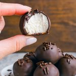 Close-up of round chocolate-coated truffles resting on parchment paper, each revealing a creamy buttercream center.