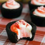 Dark chocolate cookie cups piped with minty cheesecake filling and sprinkled with crushed candy canes.