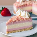 Close-up of a slice of Strawberry Crunch Cheesecake Cake, layered with creamy filling and crunchy topping, resembling a perfect Strawberry Crunch Crumble Recipe in bar form—a stunning take on Dessert Recipes Cheesecake. The vibrant pink layers highlight the irresistible Strawberry Crunch Cheesecake Bars ready to tempt every sweet tooth.