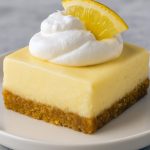 Stack of chilled lemon cheesecake bars with a golden graham crust and glossy lemon glaze—this Lemon Cheesecake Dessert looks like one of The Best Lemon Desserts, styled as portable Baked Bars Desserts and inspired by Lemon Sopapilla Cheesecake. The cut shows the creamy Lemon Cheesecake Filling, perfect for fans of Desserts With Lemon Juice, Fresh Lemon Recipes Desserts, and classic Lemon And Cream Cheese Recipes, like a bright Lemon Bar Cheesecake.