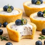Close-up of Blueberry Cheesecake Cookie Cups showing golden cookie cups piped with creamy cheesecake filling and topped with vibrant blueberry puree, illustrating the Blueberry Cheesecake Cookie Cups Recipe.