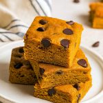 A tray of thick, chewy Pumpkin Spice Blondies studded with melty Chocolate Chip Bars, showcasing the gooey texture of a Pumpkin Blondies Recipe Easy and the cozy warmth of fall spices. Perfect for a Dessert Party, these squares echo both Chocolate Chip Blondies and a hearty Pumpkin Spice Blondie Recipe With Pumpkin Puree, with options for Vegan Pumpkin Blondies Recipe or Pumpkin Blondies Vegan versions, making this the ultimate Pumpkin Blondies Recipe.