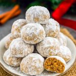 Close-up of powdered sugar-dusted gingerbread snowball cookie on a white plate, evoking festive Christmas Cookies Gingerbread, ready to complement Christmas Casserole Recipes and other Easy Xmas Desserts.