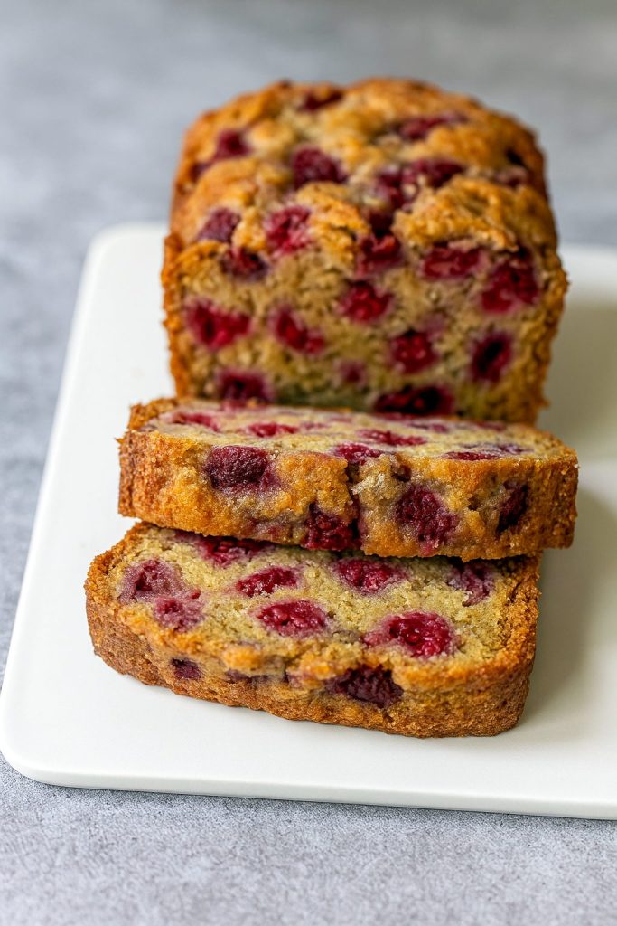 Golden loaf of Fruit Bread bursting with raspberries, reminiscent of Cloud Bread lightness, perfect for Raspberry Desserts fans.