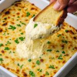 Cheesy garlic bread dip baked in a dish, served with toasted crostini and parsley on top – the perfect Bread And Butter Appetizer and Dip For Crostini with bold garlic flavor.