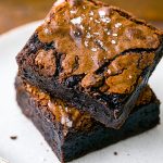 Close-up of shiny, crackly brownies stacked to highlight the fudgy center of Gooey Fudge Brownies, showcasing the deep color from the Best Brownie Recipe With Cocoa Powder.