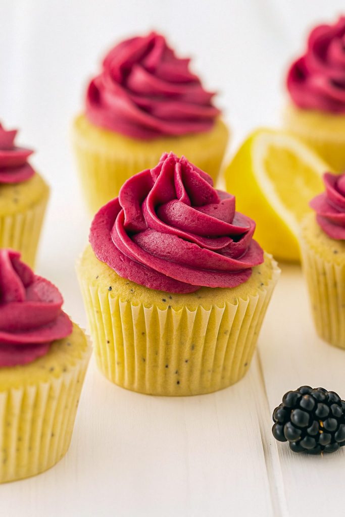A golden Cupcake speckled with poppy seeds and crowned with deep purple blackberry buttercream—pure Yummy Food Dessert magic. This festive scene showcases one of the best Cupcake Recipes, a must-try for lovers of Just Desserts.