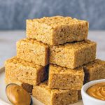 Freshly cut squares of Peanut Butter Rice Crispies, showcasing the gooey interior of these Peanut Butter Rice Krispie Treats drizzled with melted butter.