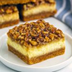 Golden-hued Pecan Pie Cheesecake Bars arranged on a serving platter, each square showcasing rich layers of cheesecake and pecan pie topping—an unexpected Coconut Dessert twist for a fresh take on classic flavors.
