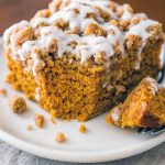 A slice of spiced pumpkin coffee cake with a golden streusel topping and vanilla glaze on a wooden board, illustrating a perfect fall treat. This photo showcases a Pumpkin Spice Coffee Cake Recipe, echoes a cozy Pumpkin Spice Latte Cake Recipe, and teaches How To Make Pumpkin Spice Latte Cake, while highlighting top Pumpkin Coffee Cake Recipes, an easy 3-ingredient Pumpkin Spice Cake, a festive Pumpkin Spice Coffee Cake Bundt, beloved Crumb Coffee Cakes, the ultimate Streusel Coffee Cake, and classic Pumpkin Coffee Cakes.