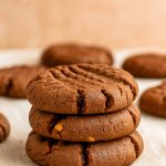 Four thick, crisscross-patterned cookies featuring deep chocolate dough and swirls of peanut butter, cooling on a wire rack.