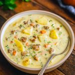 Hearty sausage and potato soup in a rustic bowl, garnished with parsley, showcasing tender potatoes and savory sausage in a creamy broth; the ultimate cozy winter meal.