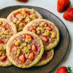 Close-up of Strawberry Crunch Cookies showing a crisp pink strawberry coating and white chocolate chips nestled in a soft, chewy center.