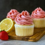 A dozen bright yellow lemon cupcakes topped with swirls of pink Strawberry Lemon Frosting, showcasing delightful Summer Dessert Cupcakes, ideal Spring Cupcakes Easy, combining Things To Bake With Lemons and Spring Flavors Sweets for Fun Yummy Desserts; these treats double as Easy Treats To Sell Bake Sale, perfect Summer Treats Recipes and Spring Themed Food Ideas.